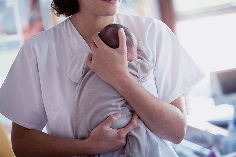 Woman holds baby up against her chest