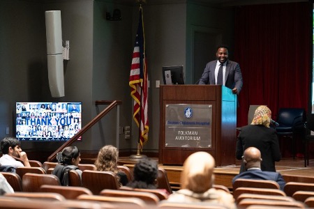 A man stands at a podium in front of an audience at the first Fenwick Institute symposium.